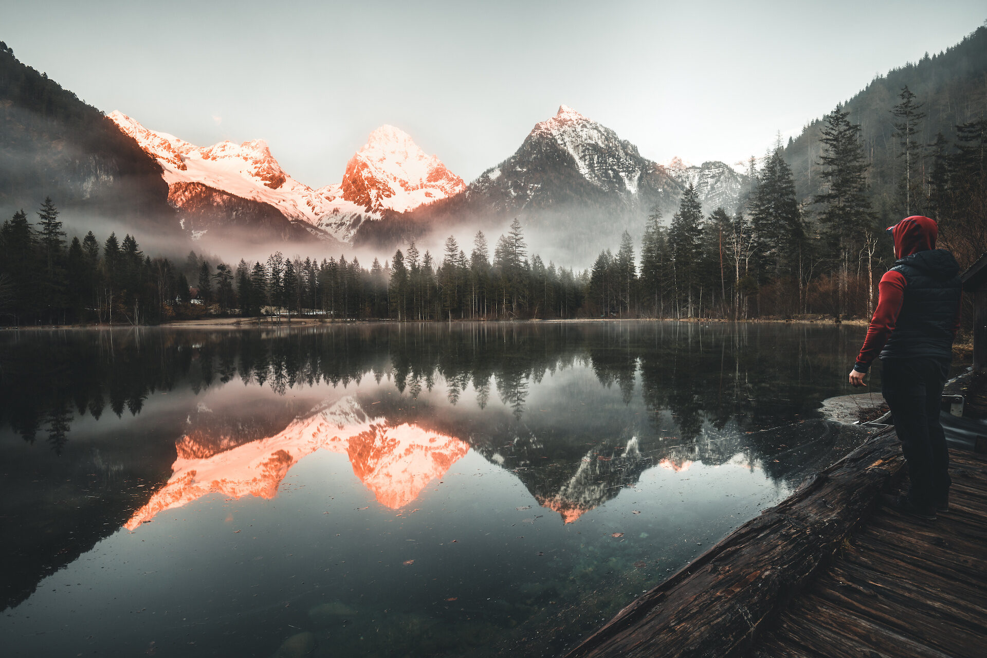 male Hiker standing at Mountain Lake schiederweiher watching the Sunrise in Austria